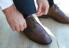 man lacing brown dress shoes