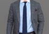 A man wearing a blue shirt & gray suit